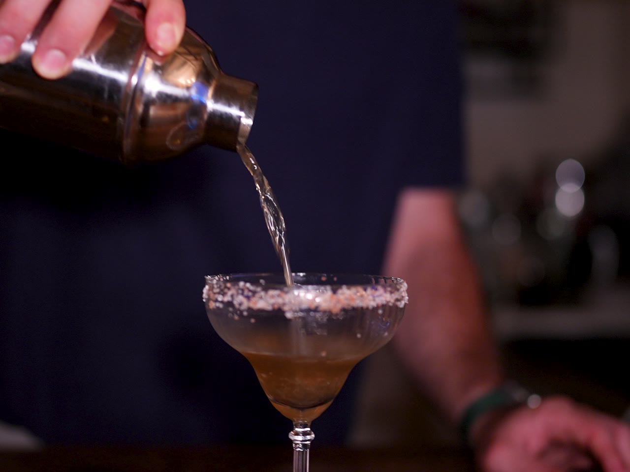 A cocktail strained from the shaker into a salt-rimmed glass